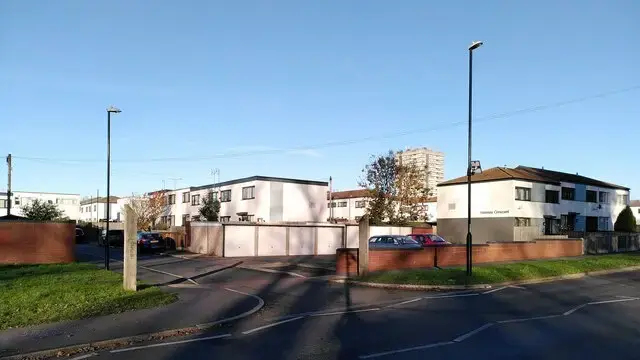 A curving street of postwar houses at Manor Farm, Coventry, with garages and parking set apart from the front doors