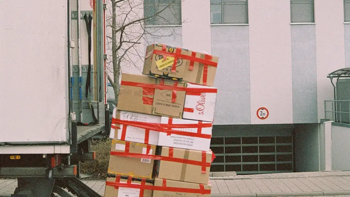 A pallet of boxes lowered on a lorry tail lift outside business premises